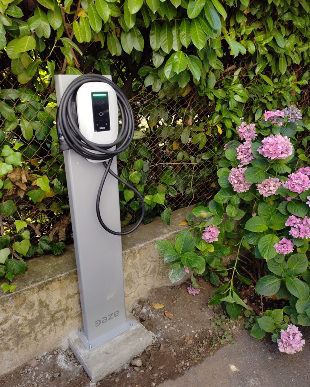 Borne de recharge DAZE Home 7,4 kW sur poteau dédié intégré dans un massif d'hortensias à Valence